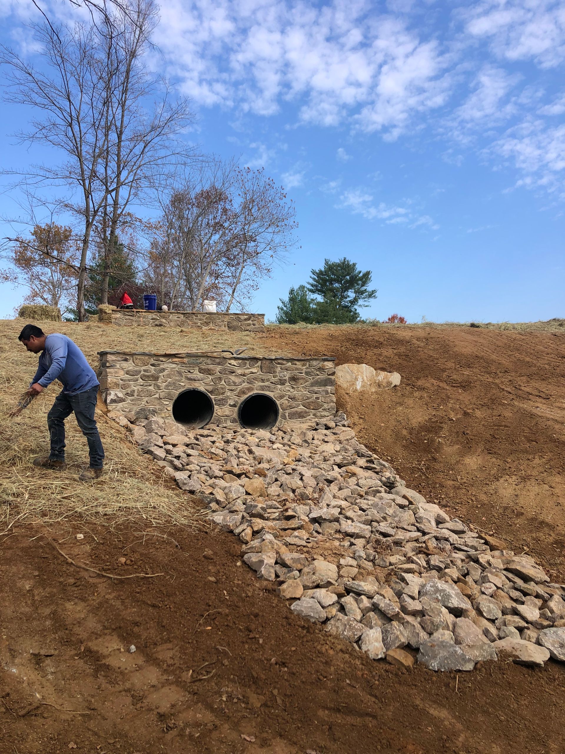A man is standing next to a pile of rocks in a field.
