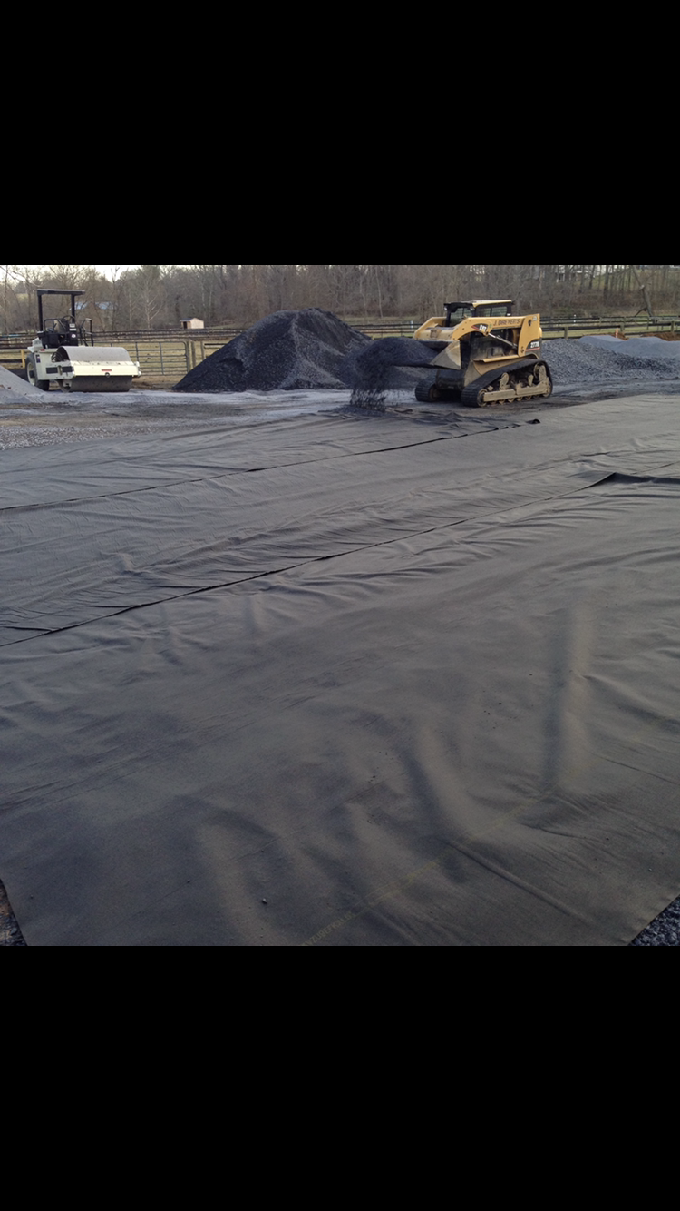 A bulldozer is moving a pile of dirt in a field.
