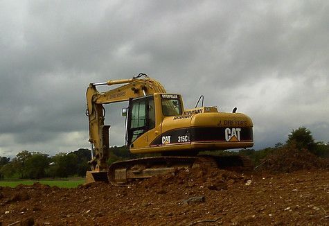 A yellow cat excavator is working in a dirt field