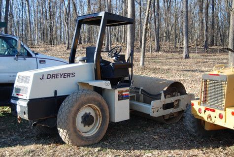 A j. dreyers asphalt roller is parked next to a truck.