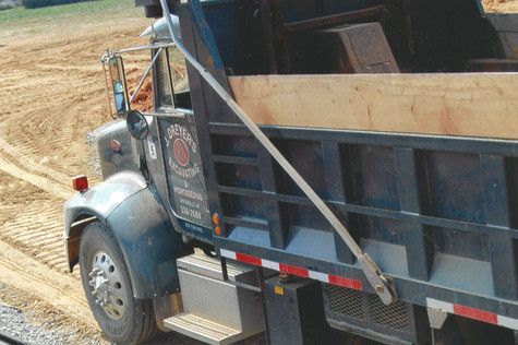 A dump truck is parked in a dirt field.