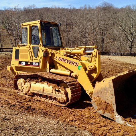 A yellow bulldozer is sitting in a dirt field.
