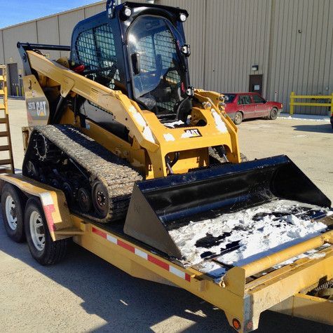 A bulldozer is on a trailer with snow on it
