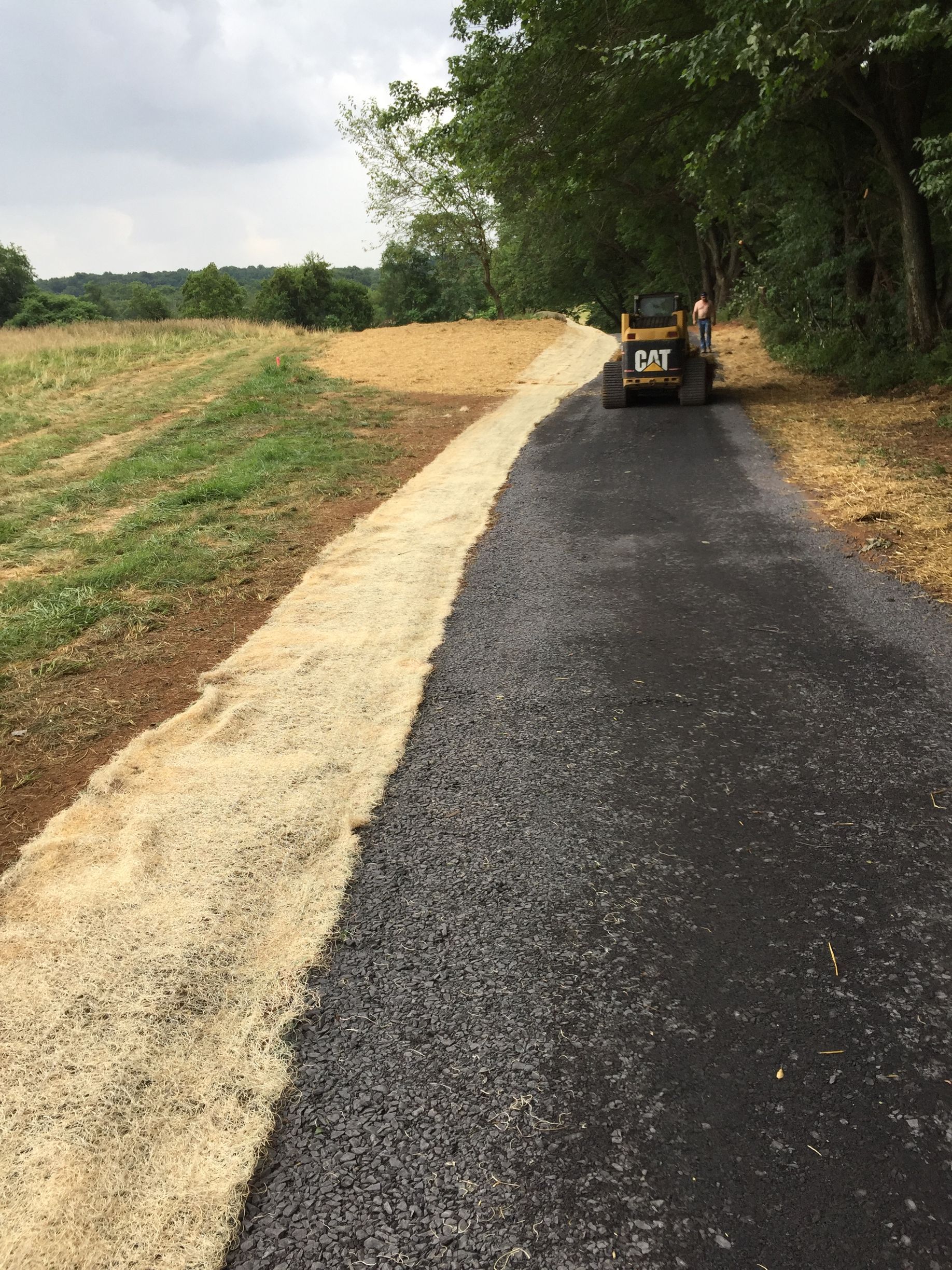 A tractor is driving down a road next to a field.