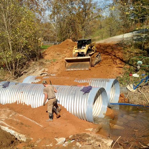 A man is standing in front of a bulldozer that is moving dirt.