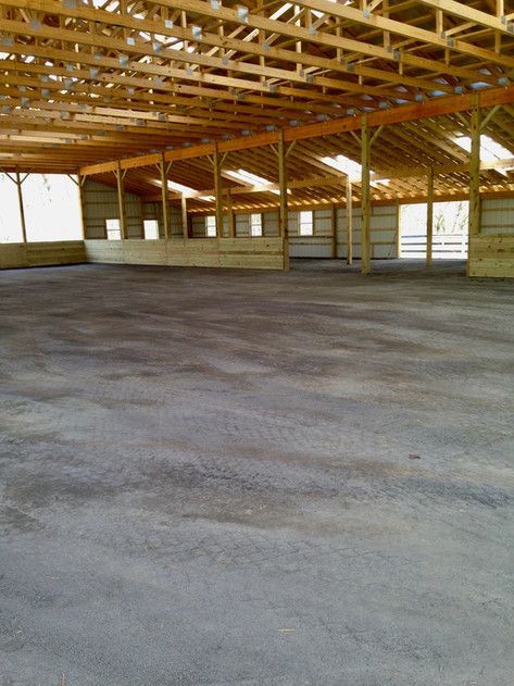 An empty building with a concrete floor and wooden beams