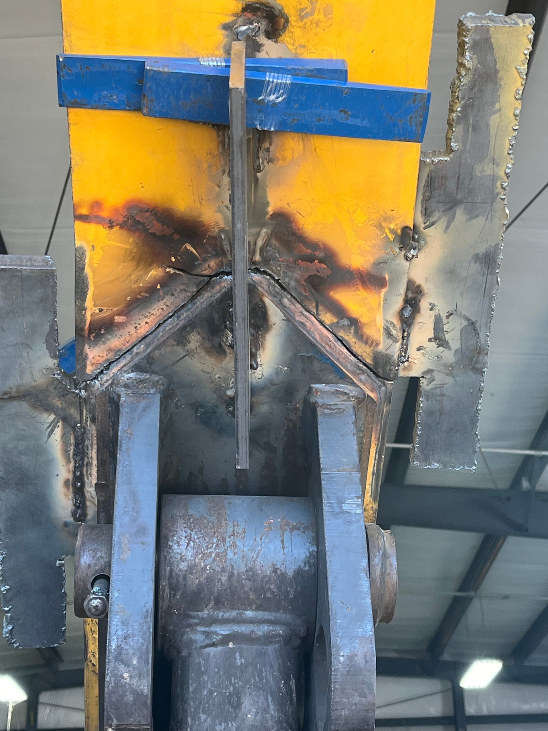 Construction site with metal framing, gray concrete walls, a lift, and dirt ground.