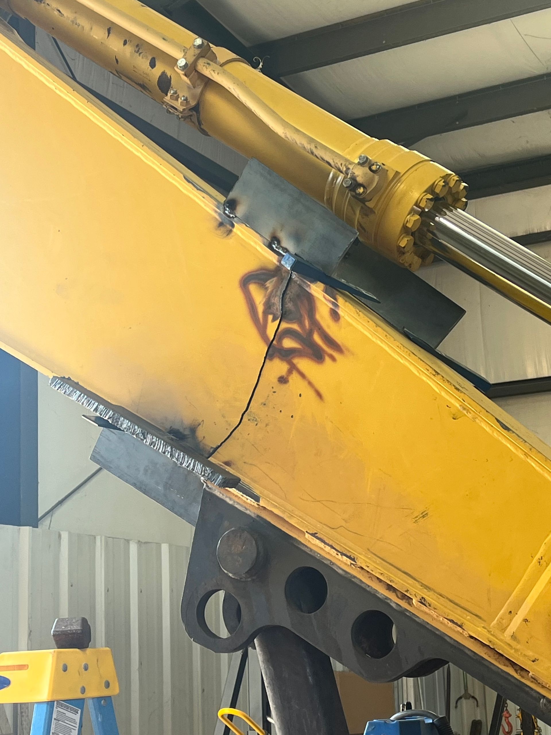Yellow excavator arm with welding repair.