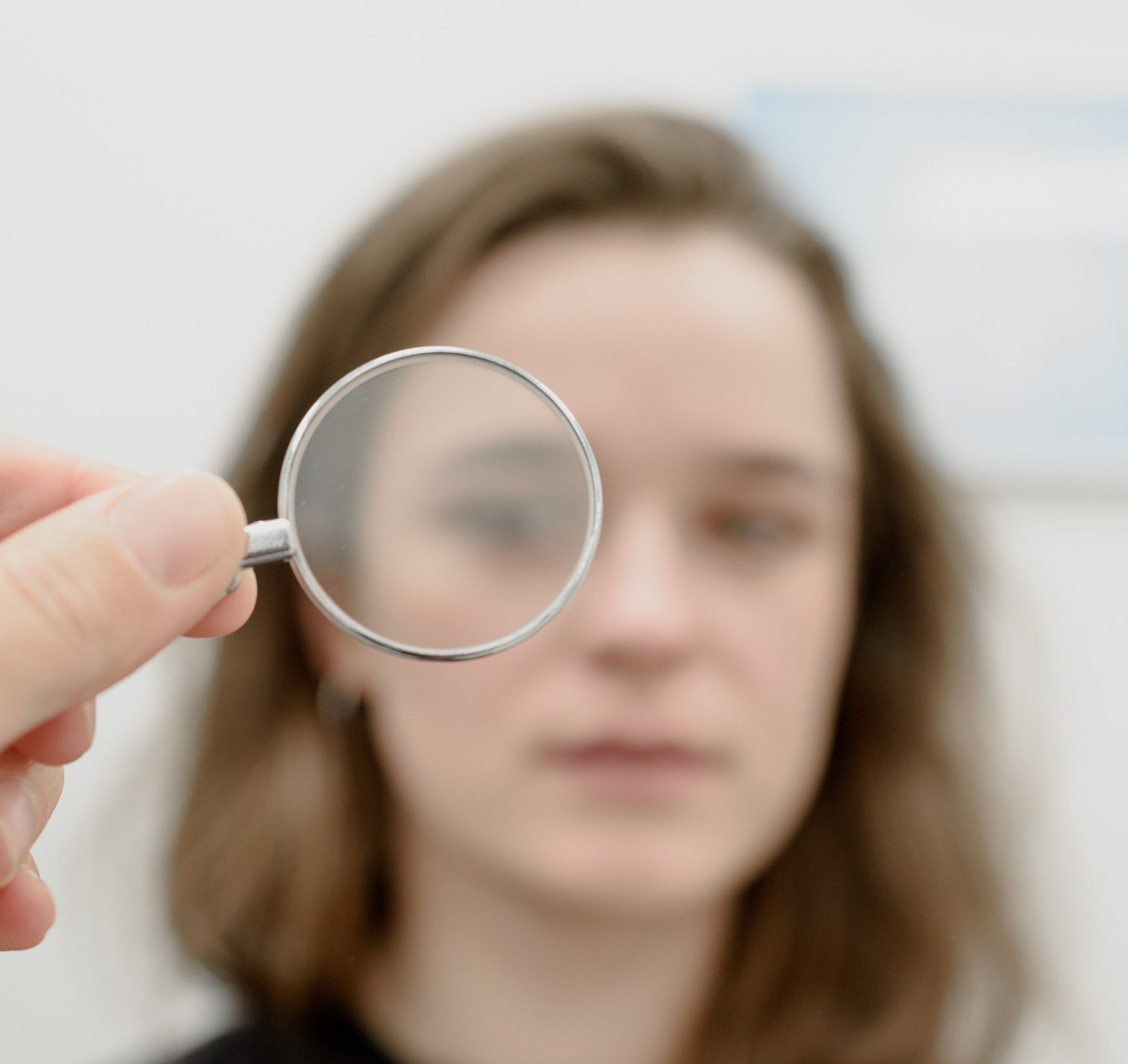 Blurred image of lady through handheld optometry lens.