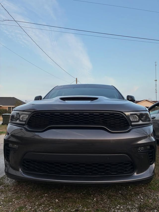 A front-facing view of a dark gray Dodge Durango SUV parked outdoors on a gravel lot under a clear blue sky.