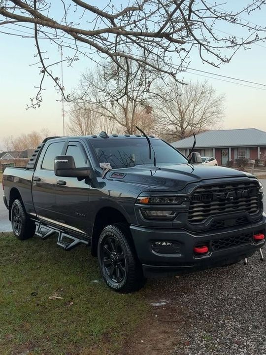 Dark gray Ram pickup truck parked on green grass; residential setting.