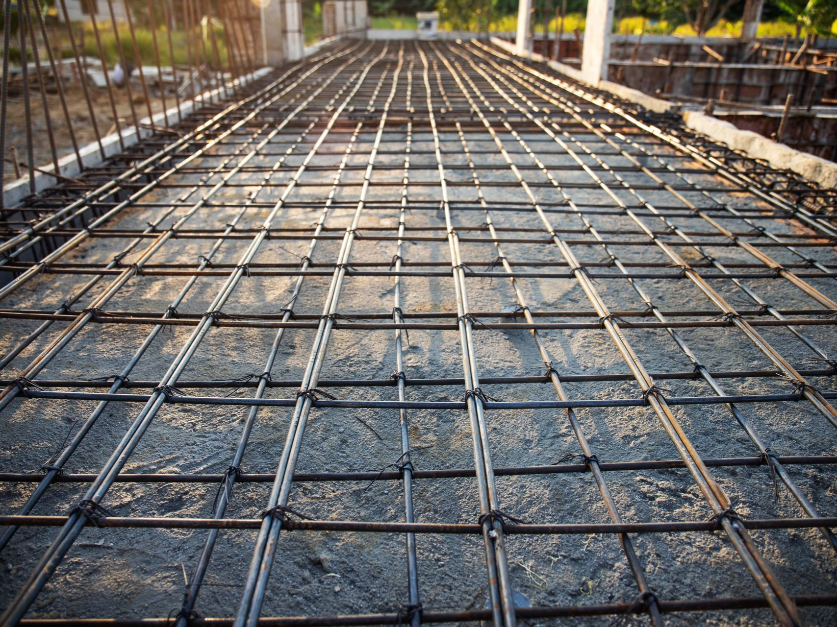 Reinforced steel rebar grid on a concrete slab, ready for pouring.