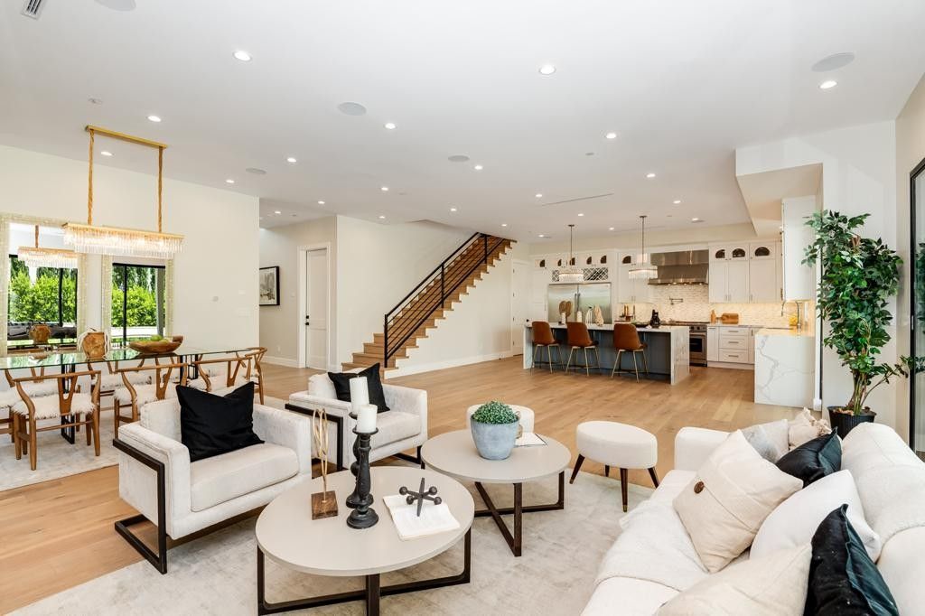 Spacious, open-plan living area with kitchen, dining, and seating areas; light wood floors, neutral tones.