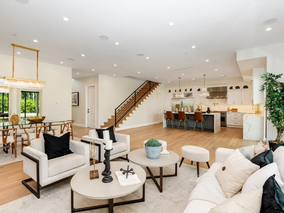 Open-concept living space with a kitchen, dining area, and living room; light wood floors, neutral colors, modern furniture.