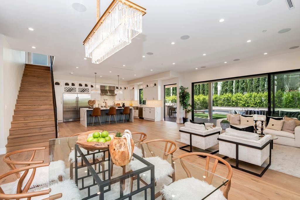 Open-concept living space with dining area, kitchen, and living room. Large glass doors overlook a yard.