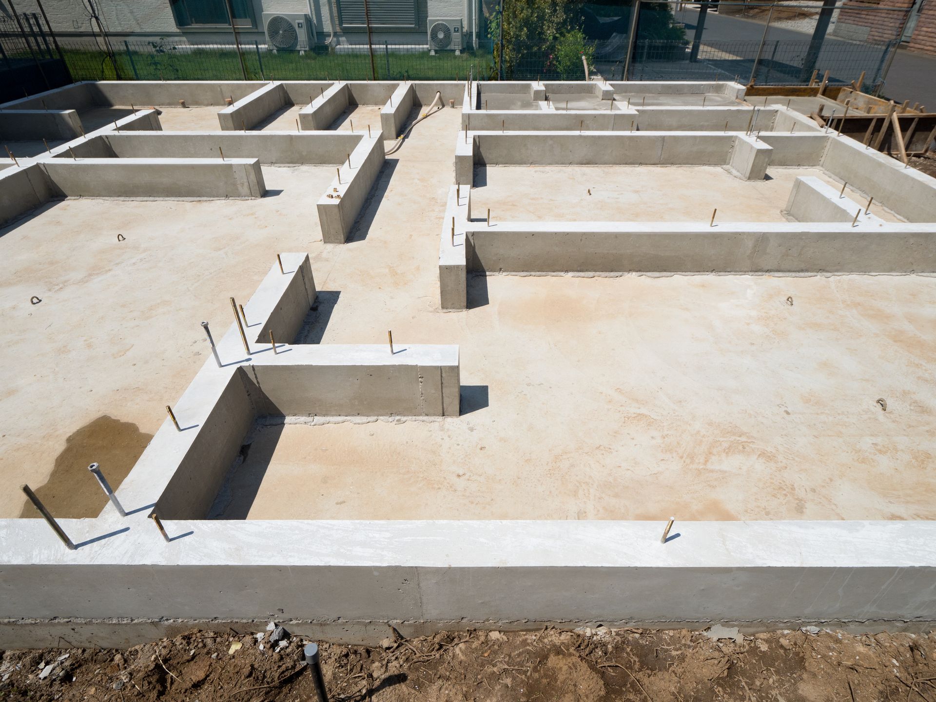 Concrete foundation of a building under construction, with exposed framework and interior spaces.