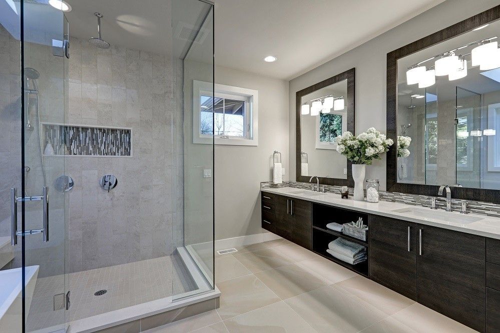 Modern bathroom with glass shower, double vanity, and neutral color scheme.