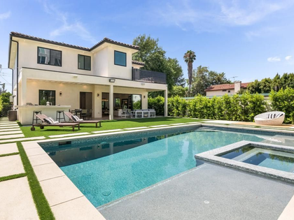 Backyard with pool, spa, and patio with lounge chairs. Modern two-story house with green lawn.