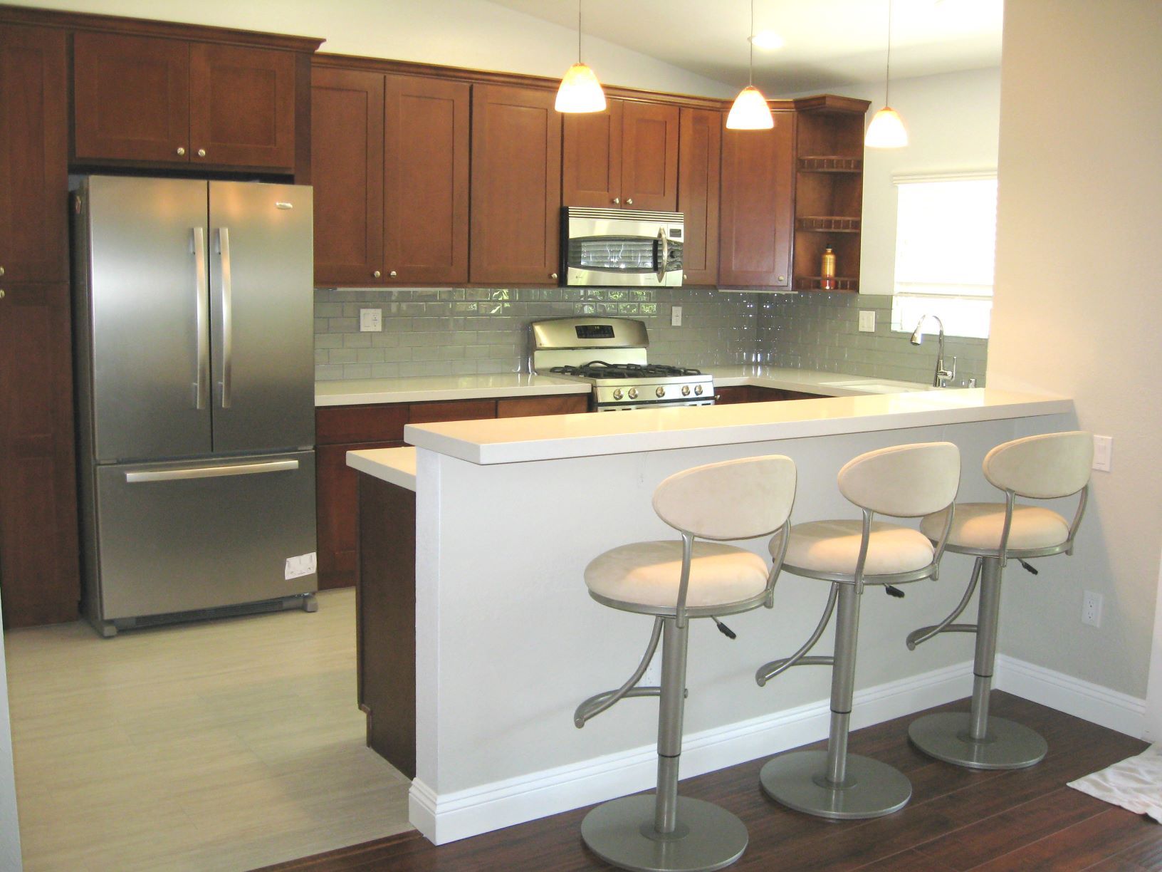 Modern kitchen with stainless steel appliances, dark wood cabinets, and bar seating.