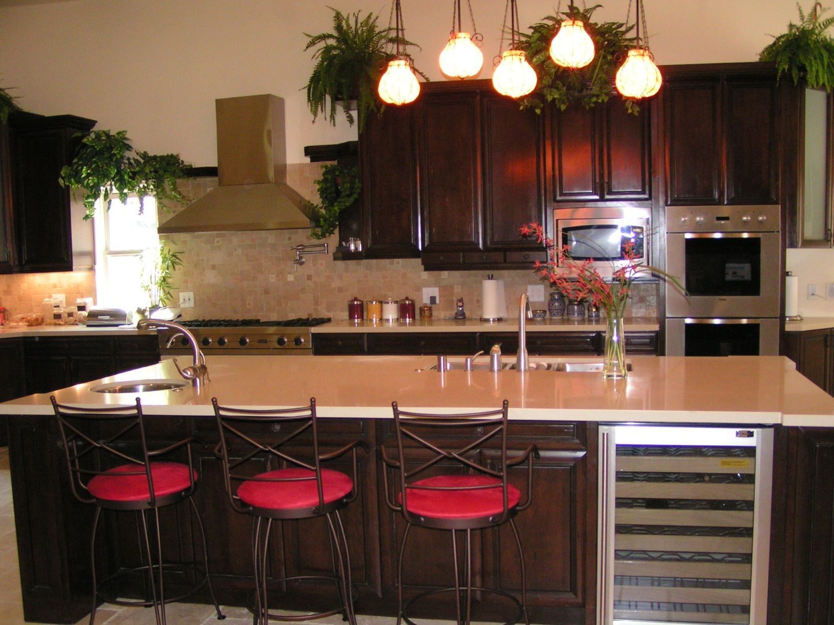 Kitchen with dark wood cabinets, island with red bar stools, and overhead lighting.