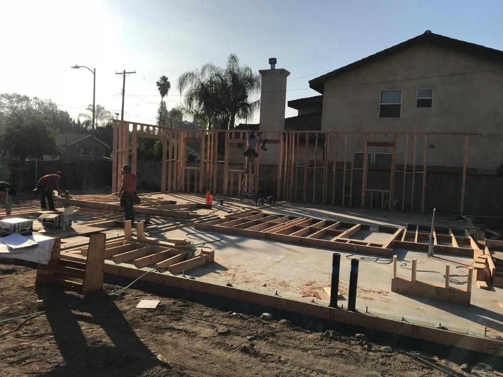 Construction site with wooden framing; workers building a house, sunny day.