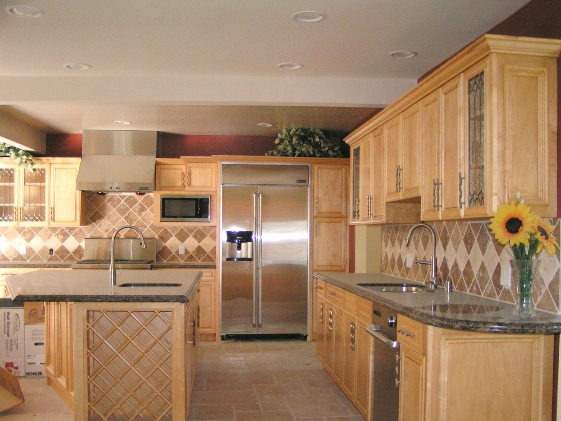 Spacious kitchen with light wood cabinets, stainless steel appliances, and patterned backsplash.