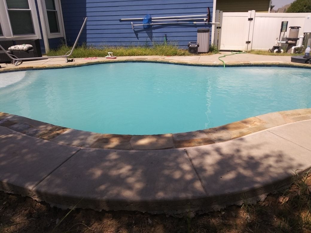 A large swimming pool with a blue house in the background.