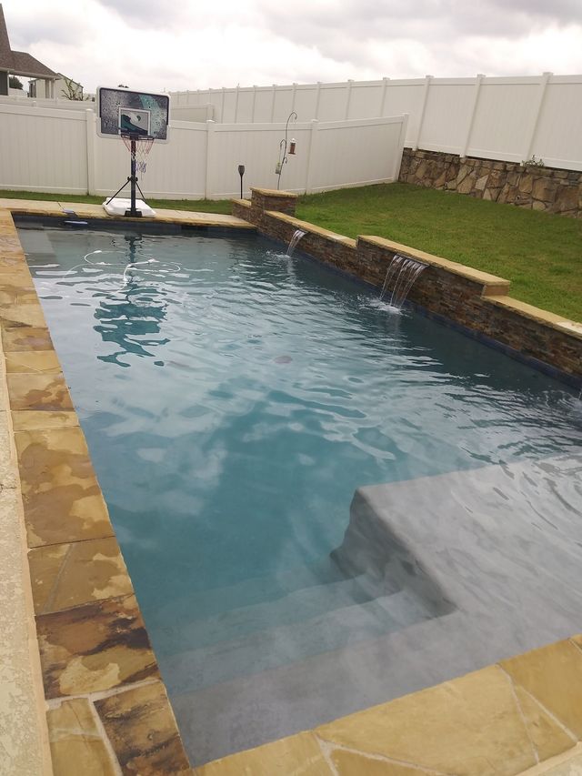 A large swimming pool with a basketball hoop in the backyard.