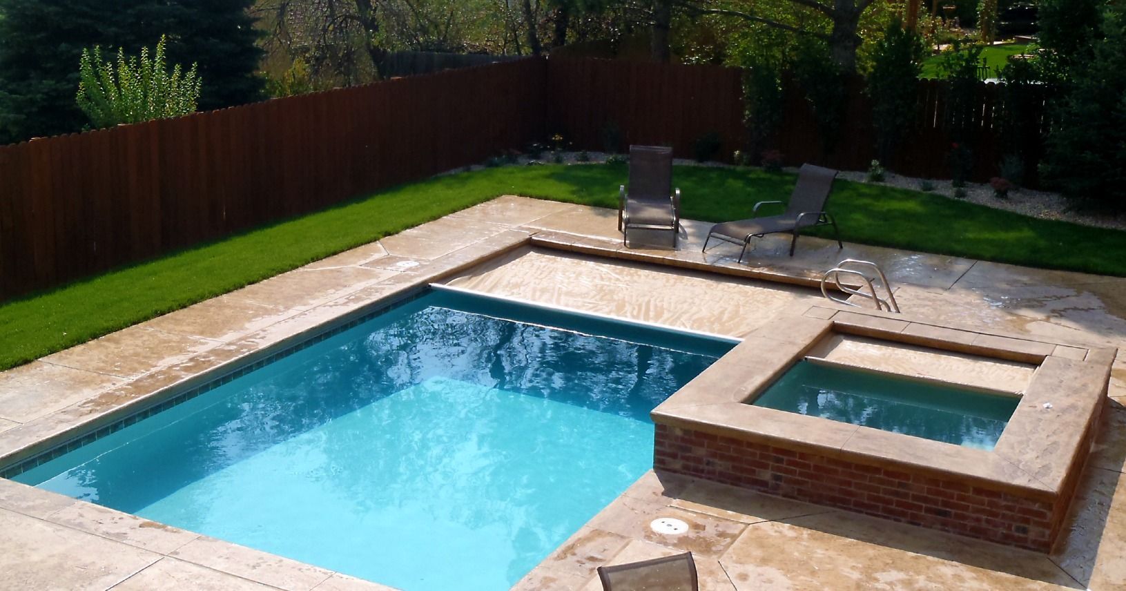 A large swimming pool with a hot tub in the backyard