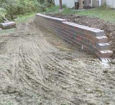 A brick wall is being built in a dirt field.