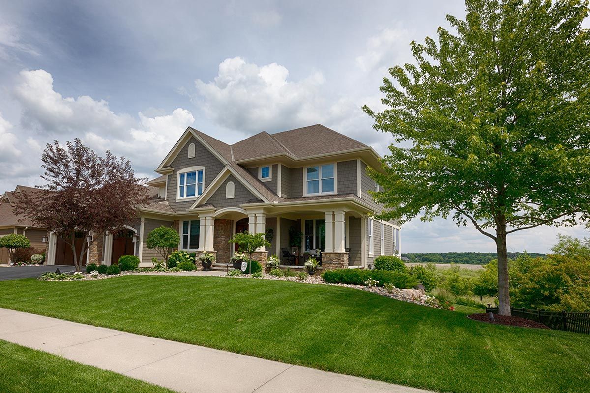 A large house with a lush green lawn and a tree in front of it