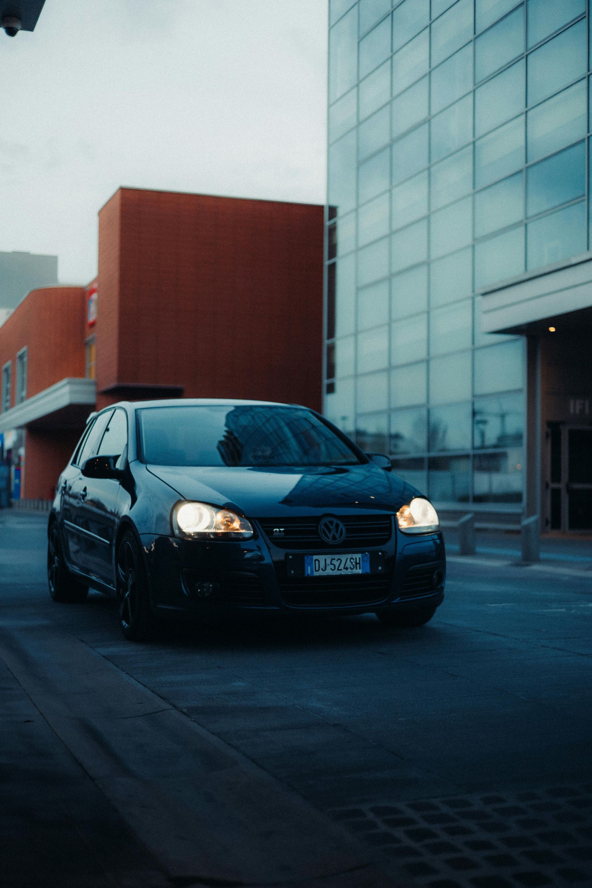 A black car is parked in front of a building.