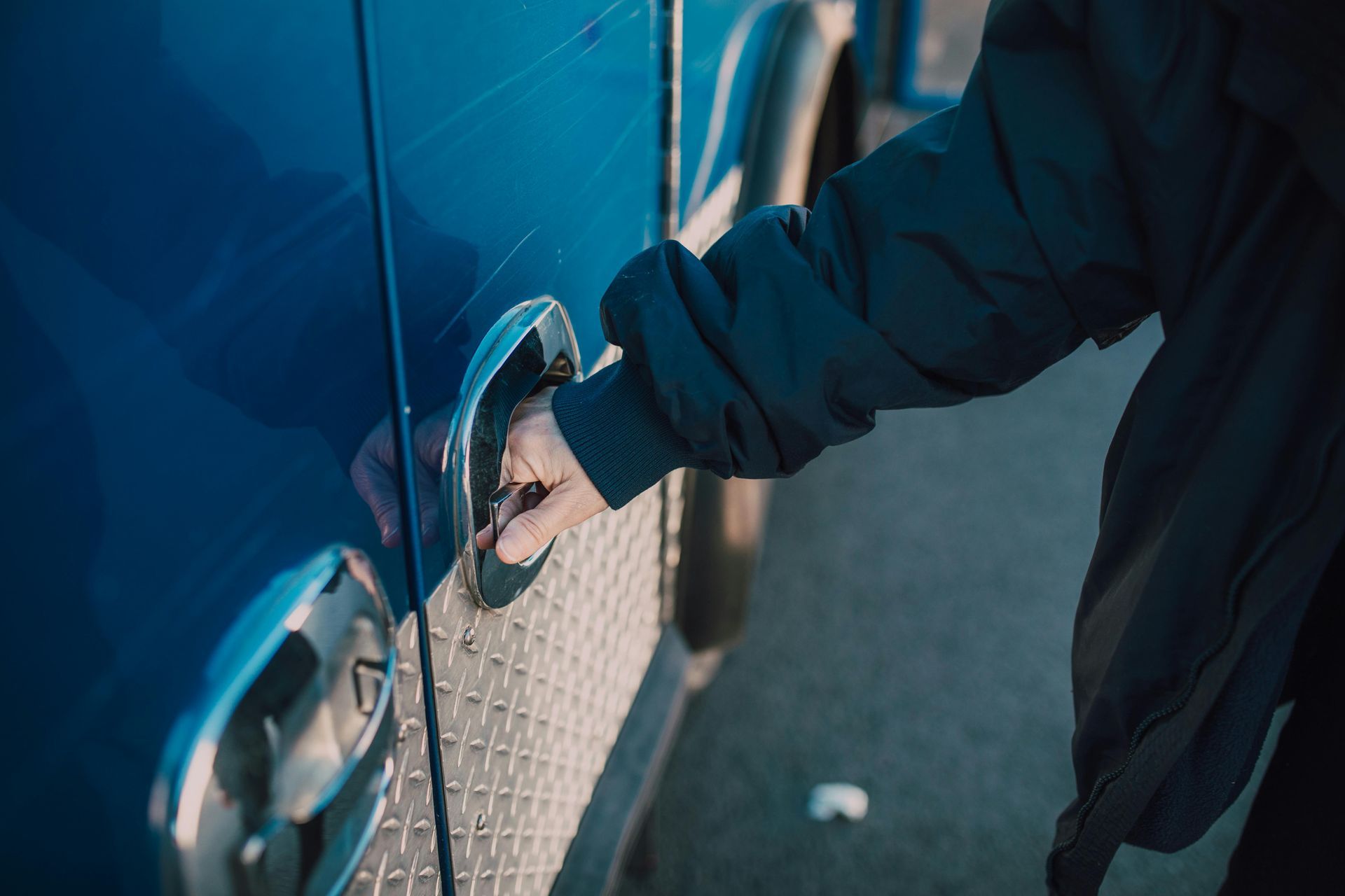 A person is opening the door of a blue truck.