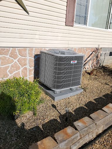 A large air conditioner is sitting on the side of a house.