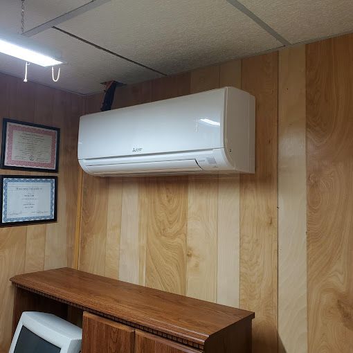 A white air conditioner is hanging from the ceiling in a room with wood paneling.