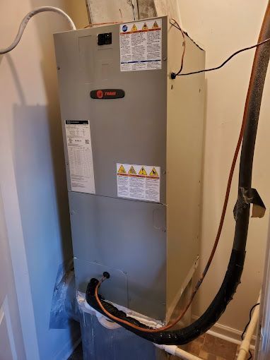 An air conditioner is sitting in a room next to a wall.