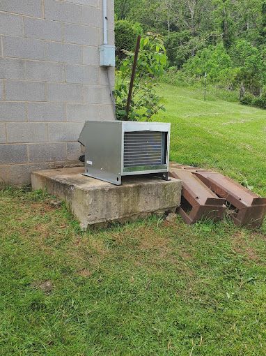 A small air conditioner is sitting on the side of a brick building.