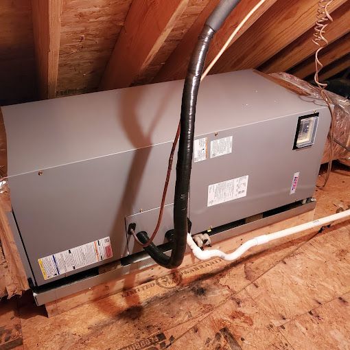 An air conditioner is sitting in the attic of a house.