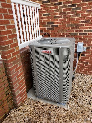 An air conditioner is sitting on the side of a brick building.