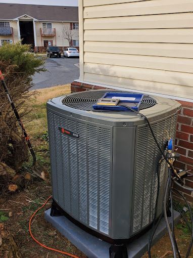 A large air conditioner is sitting outside of a house.