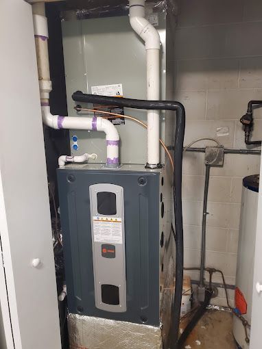 A gas heater is sitting in a room next to a water heater.