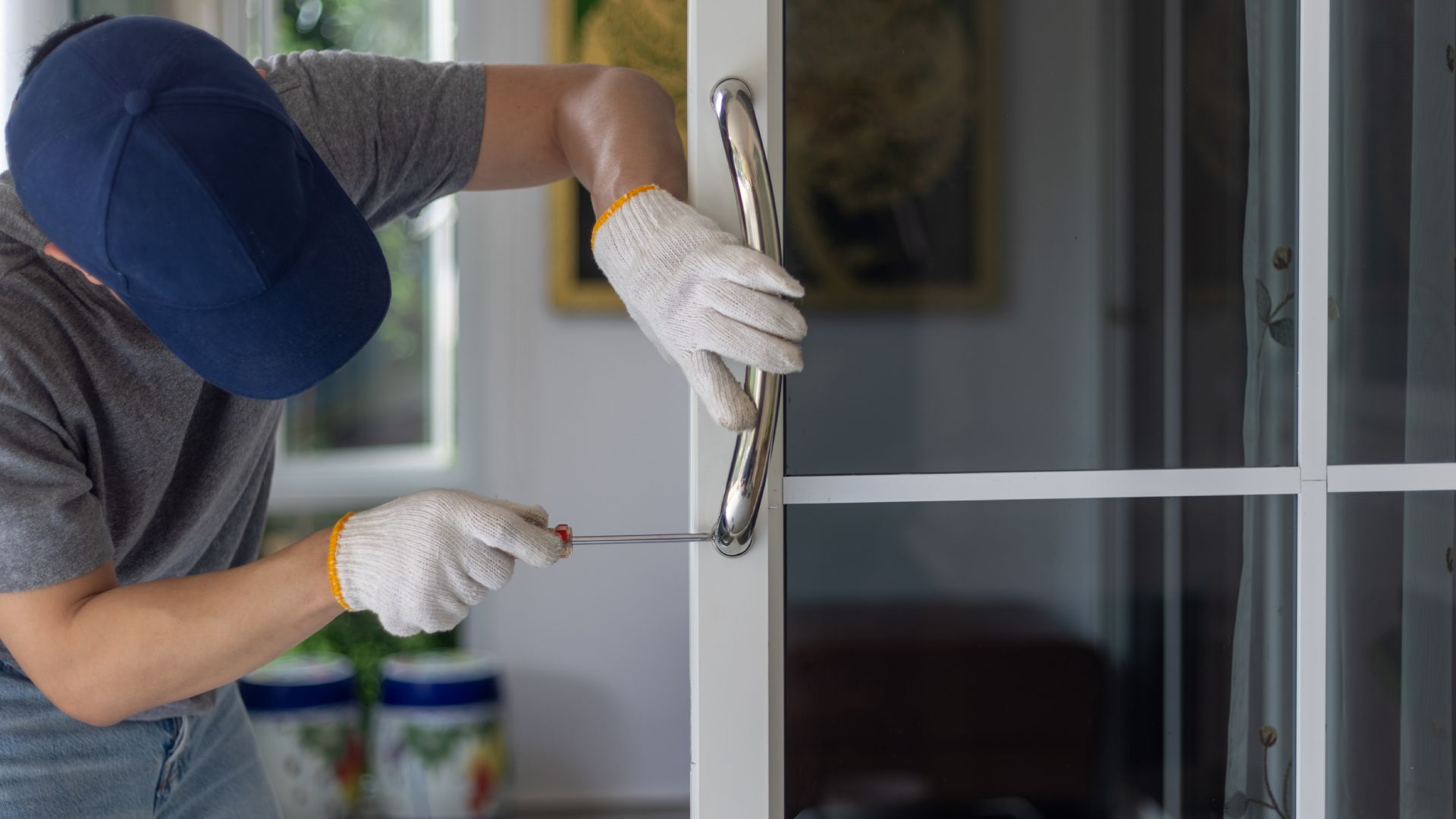 A man is fixing a sliding glass door with a screwdriver.