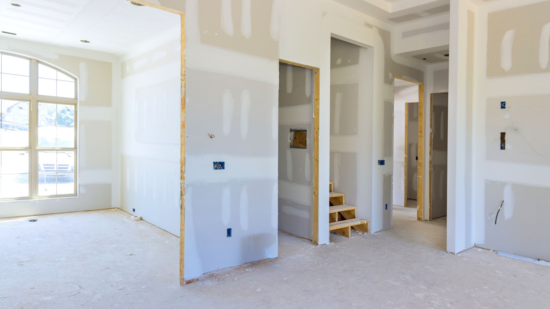 A room in a house under construction with drywall on the walls.