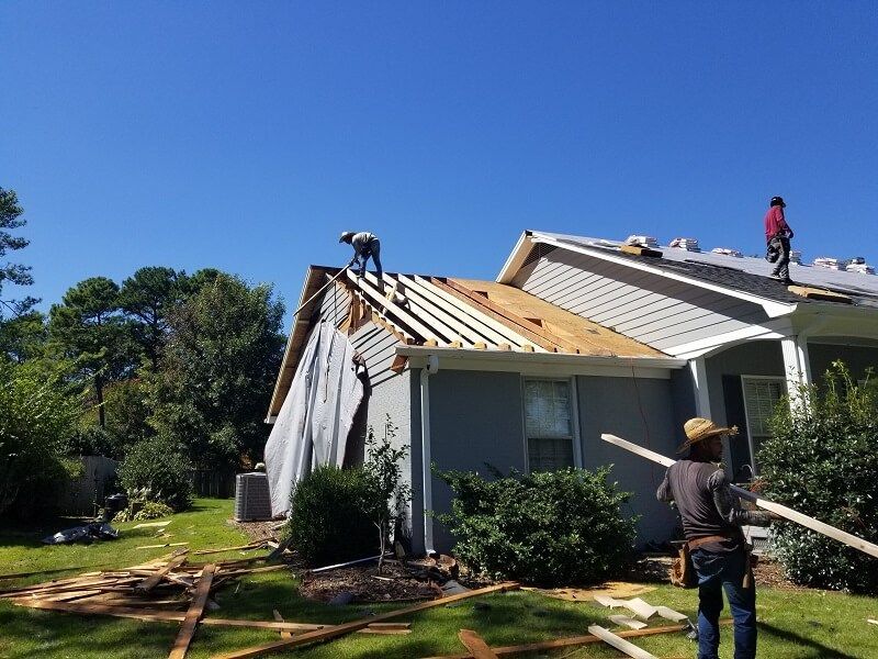 A man in a yellow vest is working on a roof.