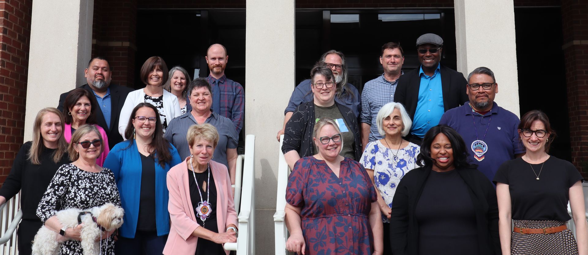Group photo of people on a building's steps; many smiling at the camera.