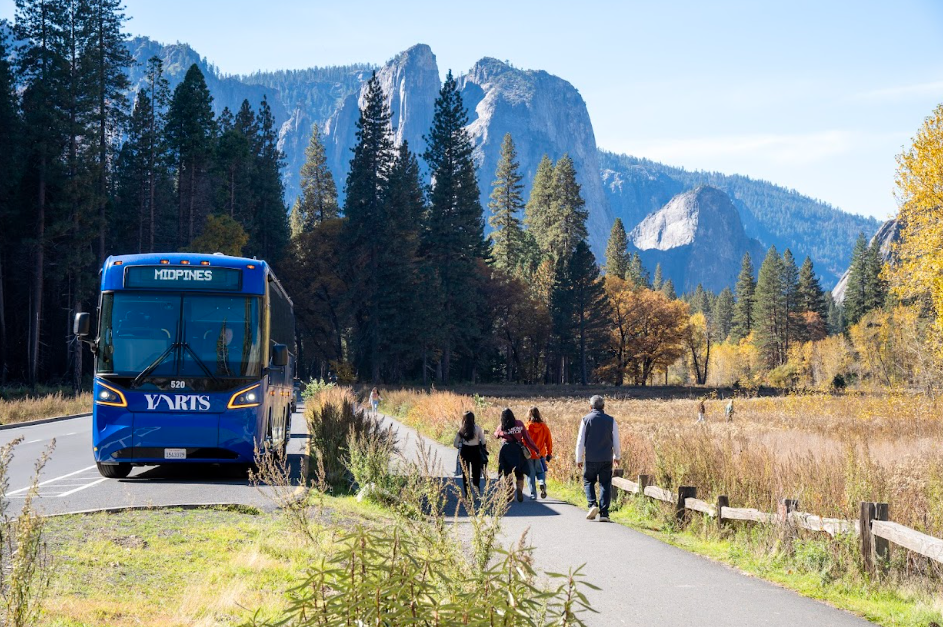 A YARTS bus parked on a road with a mountain and trees in the background. The bus is blue and green.