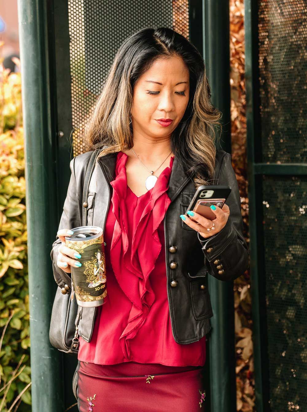 Woman holding a cup and looking at her phone.