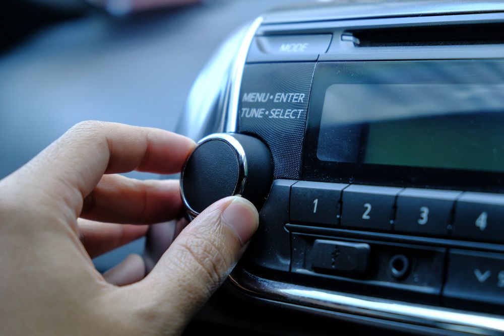 A person is adjusting the volume on a car radio.