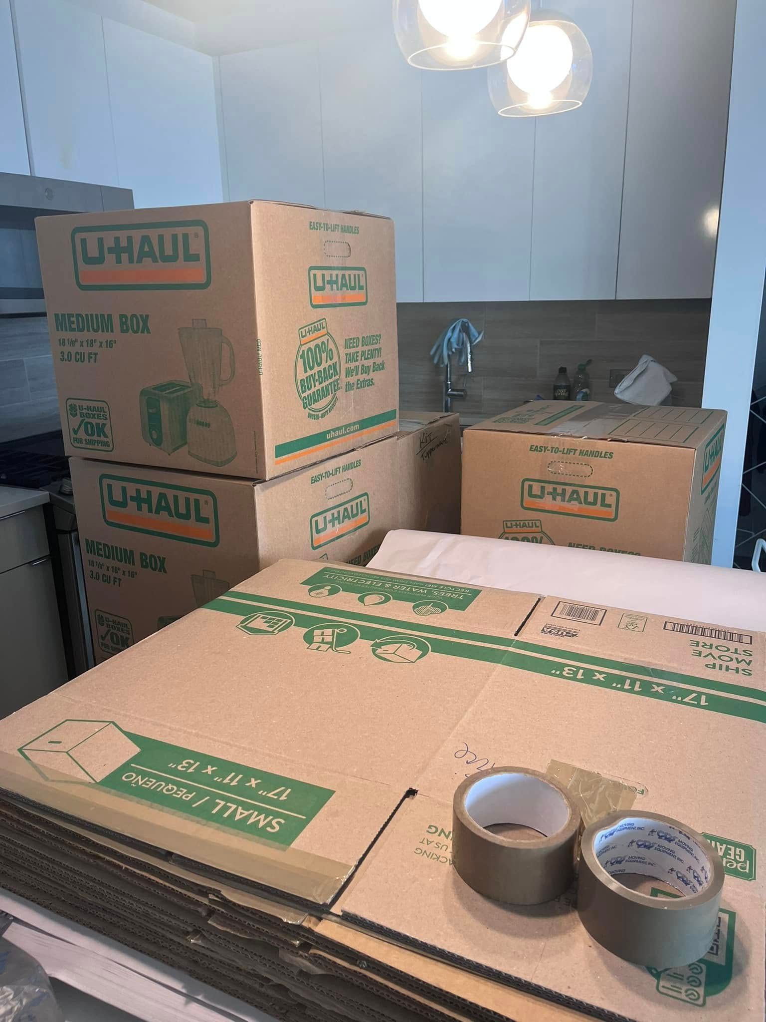 A person wearing gray gloves uses clear packing tape to seal a cardboard box.