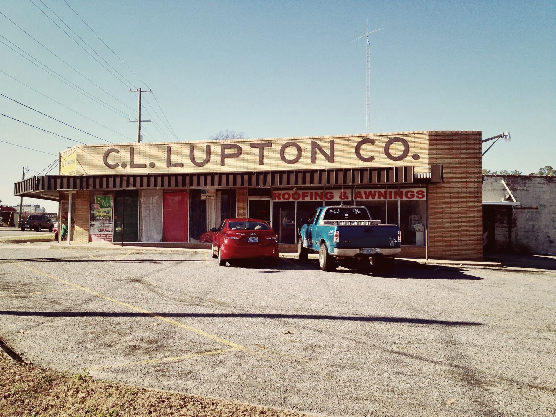 two cars are parked in front of a building that says c.l. lupton co.